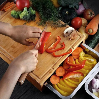 Planche à découper bambou avec  à tiroirs 
une personne coupant des légumes sur la planche dessous le tiroir ouvert rempli de légumes autour des légumes en attenécouper