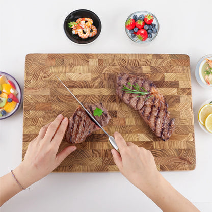  planche à découper en bois de teck  des mains avec un couteau  et coupant une tranche de  boeuf quelques coupelles autour de la planche